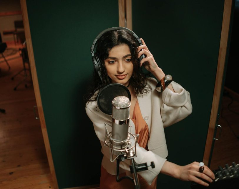Professional female musician recording vocals in a music studio.